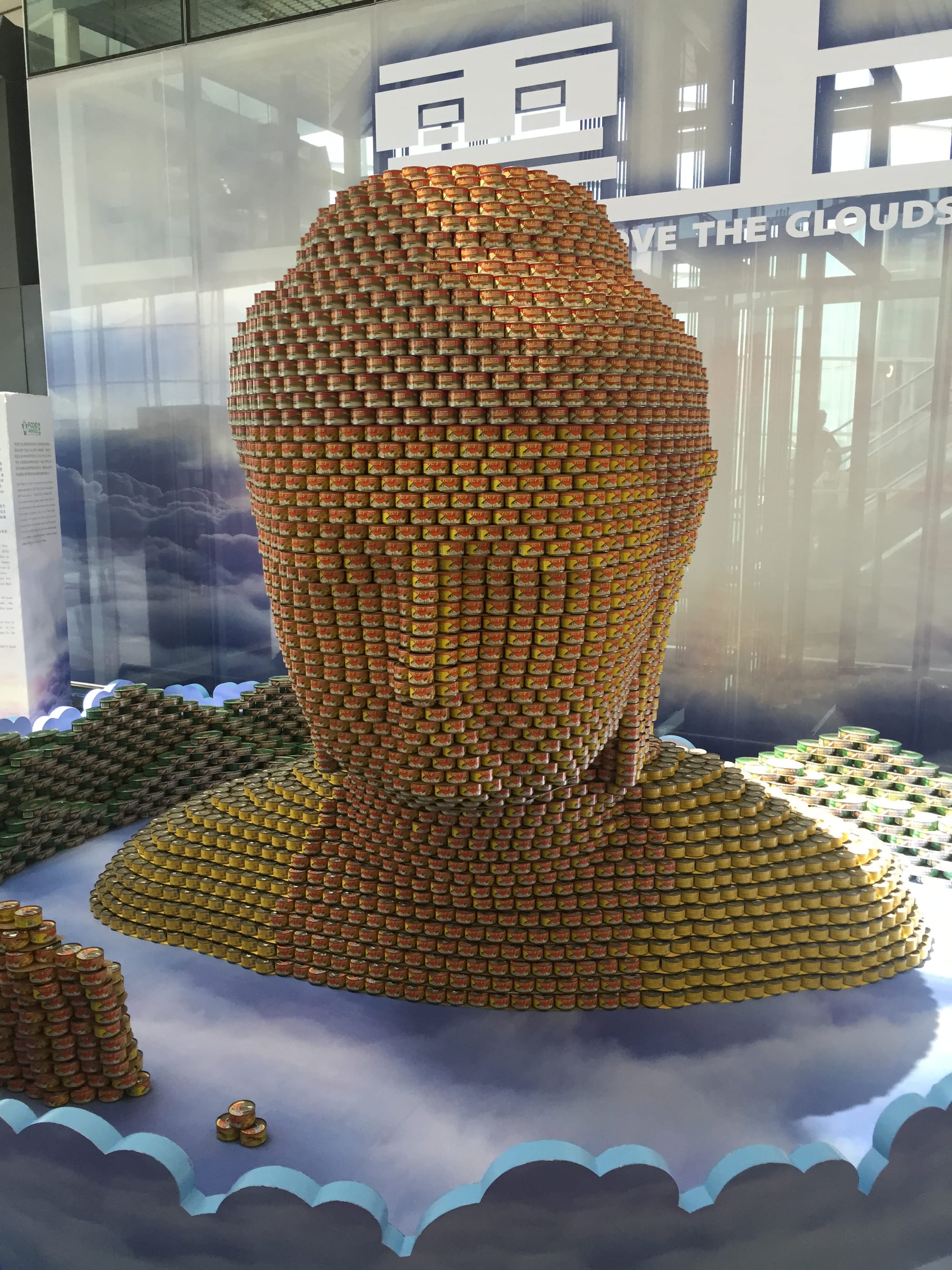 Photo by Author — a Buddha head built out of tins of seafood — Hong Kong International Airport 香港國際機場 (HKG)