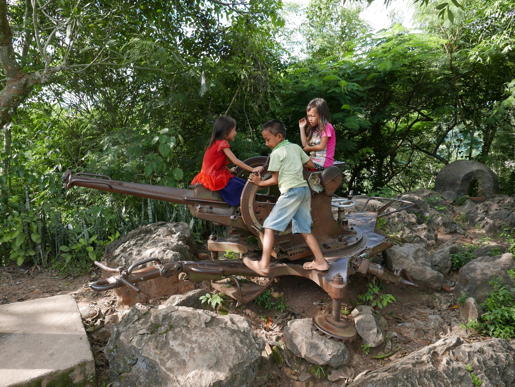 Photo by Author — kids at play on an old anti-aircraft gun — Mount Phousi, Luang Prabang (ຫລວງພະບາງ/ຫຼວງພະບາງ), Laos