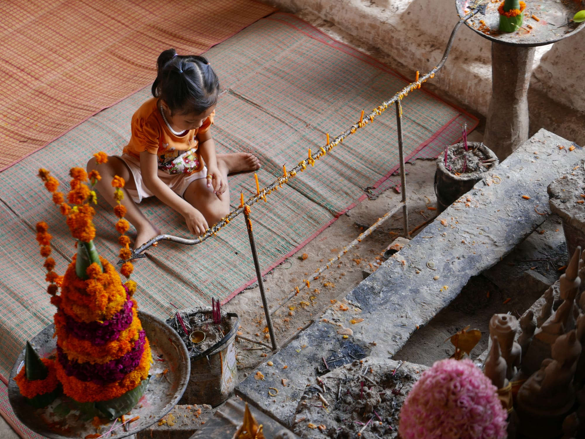 Photo by Author — a small girl at a shrine in the Tham Ting (Tam Ting)/Pak Ou (ถ้ำติ่ง) Caves, Laos