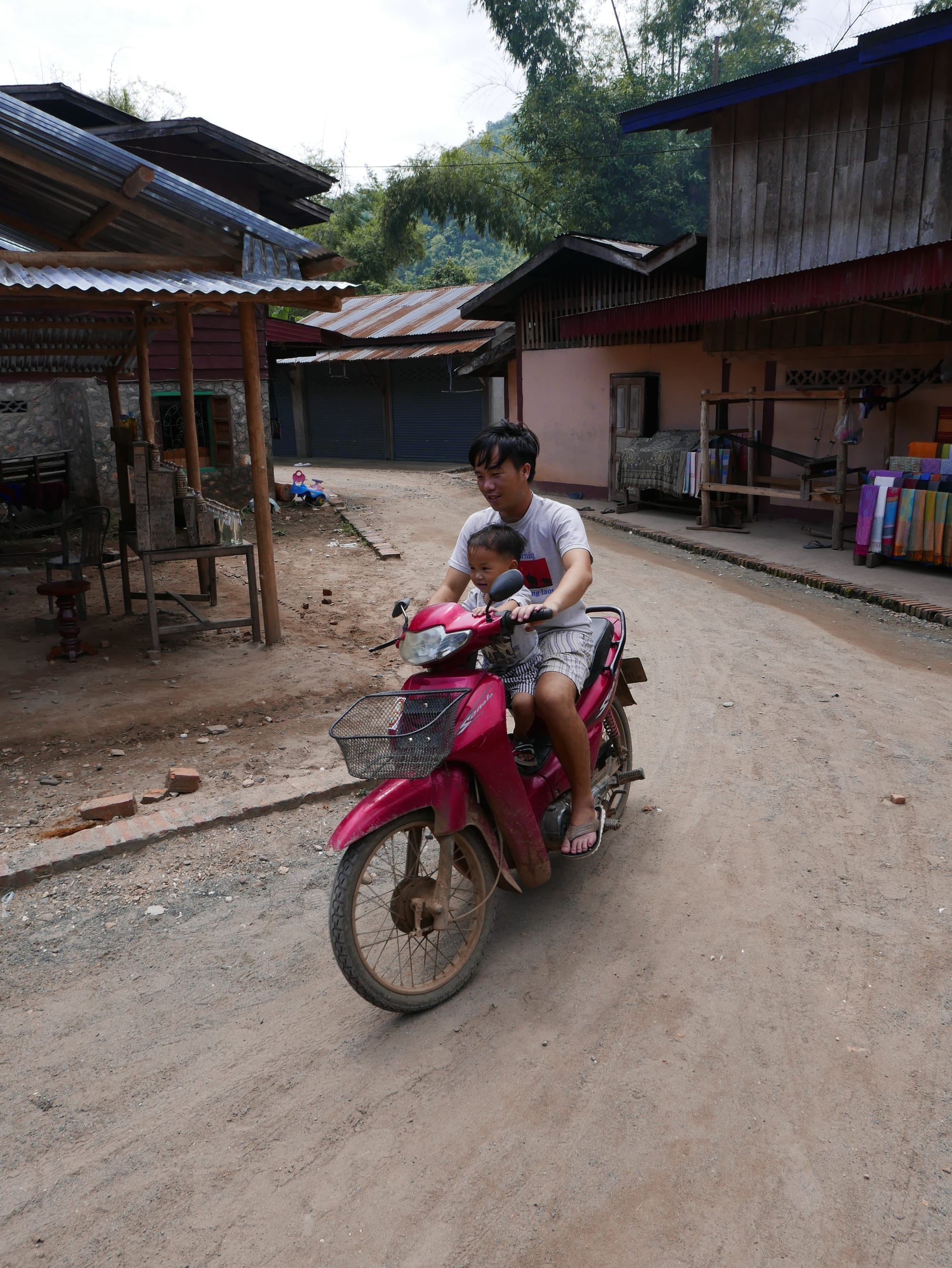 Photo by Author — a local kid and his dad (presumably) — Ban Xanghai (ບ້ານຊຽງຮາຍ): Liquor & Silk Village, Luang Prabang (ຫລວງພະບາງ/ຫຼວງພະບາງ), Laos