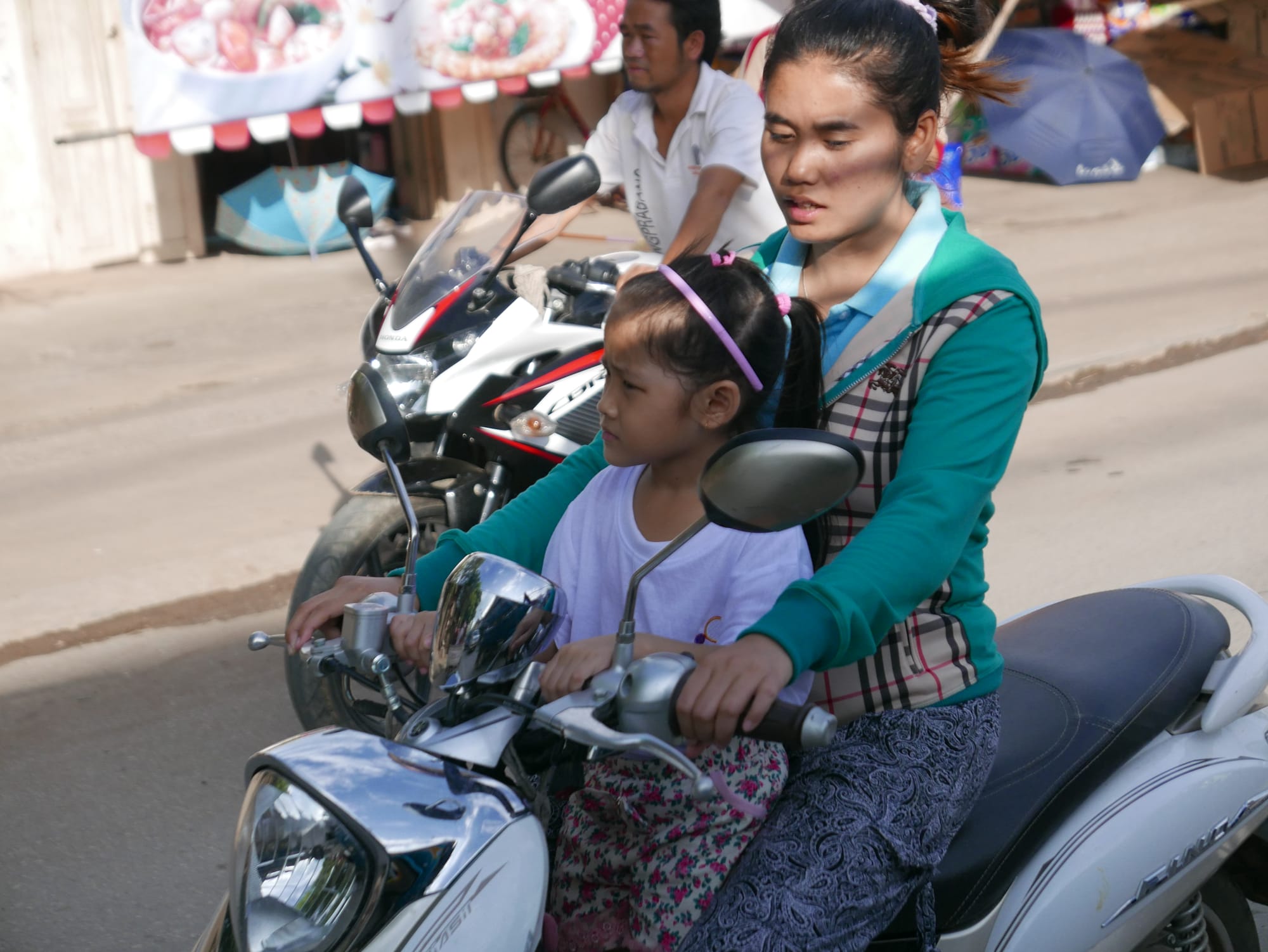 Photo by Author — motorbikes in Luang Prabang (ຫລວງພະບາງ/ຫຼວງພະບາງ), Laos — two-up, start them young